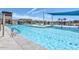 Wide view of the clear swimming pool with lounge seating and shade structures at the community center at 22960 N 94Th Ln, Peoria, AZ 85383