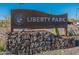 View of the Liberty Park community sign featuring decorative rock base and desert plants at 22960 N 94Th Ln, Peoria, AZ 85383