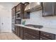 Close up of a modern kitchen with stainless steel appliances, a subway tile backsplash, and dark cabinetry at 22960 N 94Th Ln, Peoria, AZ 85383