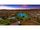 Stunning aerial view of a Primary-planned community featuring a lake, pool, and clubhouse at sunset at 2322 E Mews Rd, Gilbert, AZ 85298