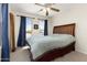 Bedroom featuring a wood headboard bed and natural light through two windows with blue curtains at 25606 W Satellite Ln, Buckeye, AZ 85326