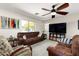 Cozy living room featuring comfortable sofas, a ceiling fan, and a large television at 25606 W Satellite Ln, Buckeye, AZ 85326