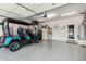 Spacious garage with epoxy flooring, custom cabinetry, and a vibrant blue golf cart parked inside at 30266 N Royal Oak Way, San Tan Valley, AZ 85143