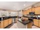 A spacious kitchen featuring wood cabinets, black countertops, stainless steel appliances and an eat-in kitchen island at 3519 E Bridgeport Pkwy, Gilbert, AZ 85295