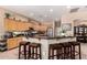 A kitchen featuring wood cabinets, black countertops, and an extended breakfast bar with leather upholstered stools at 3519 E Bridgeport Pkwy, Gilbert, AZ 85295