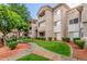 Charming condo building featuring manicured lawn, lush landscaping, and a tiled roof under a clear blue sky at 3830 E Lakewood Pkwy # 3099, Phoenix, AZ 85048