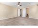 Carpeted bedroom with ceiling fan and views to a bathroom, offering a serene retreat within the home at 42213 W Santa Fe St, Maricopa, AZ 85138