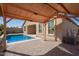 Backyard pool surrounded by patio, wooden pergola, and exterior of the home at 42213 W Santa Fe St, Maricopa, AZ 85138
