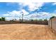 Expansive dirt backyard enclosed with block wall, with power lines and trees visible under a cloudy blue sky at 524 S Pioneer --, Mesa, AZ 85204