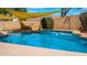 Backyard pool featuring a tile accent wall, with covered patio seating and landscaping in view at 5401 S Dove Holw, Buckeye, AZ 85326