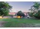 Twilight view of the backyard with large lawn, mature landscaping, and patio at 645 S Esquire Way, Mesa, AZ 85202