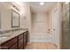 Well-lit bathroom featuring granite countertop, framed mirror, tile floors, and a tub at 645 S Esquire Way, Mesa, AZ 85202