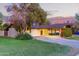 Charming single-story home with a circular driveway, lush greenery, and a vibrant red front door at 645 S Esquire Way, Mesa, AZ 85202