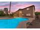 Backyard pool with stone surround against the backdrop of a two-story home with a covered patio and vibrant sunset at 704 E Gemini Pl, Chandler, AZ 85249