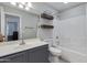 Well-lit bathroom featuring a vanity, toilet, shower, and dark wood floating shelves at 7346 E Naranja Ave, Mesa, AZ 85209