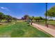 Scenic park pathway with manicured lawns, mature trees, and community signage at 7346 E Naranja Ave, Mesa, AZ 85209