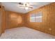 Bedroom featuring neutral carpet, wood paneling and a ceiling fan at 7654 E Calypso Ave, Mesa, AZ 85208