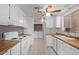 Bright kitchen with tile flooring, white cabinets, wood-style counters, and a view of laundry area at 7654 E Calypso Ave, Mesa, AZ 85208