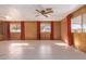Spacious living room with tile flooring, ceiling fan, views of the outdoor area, and vintage wood paneling at 7654 E Calypso Ave, Mesa, AZ 85208