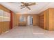 Open living room featuring tile floors, wood paneled walls, ceiling fan, and built in cabinets at 7654 E Calypso Ave, Mesa, AZ 85208