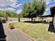 A large backyard includes gravel, lawn, mature trees, and a covered patio at 8402 N 105Th Ln, Peoria, AZ 85345