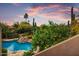 Beautiful aerial view of the pool, waterfalls, cactus, desert landscape, and sunset at 8526 E Hackamore Dr, Scottsdale, AZ 85255