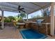 Outdoor kitchen with BBQ, bar seating, gas grill, and fire pit under pergola at 9231 W Bent Tree Dr, Peoria, AZ 85383