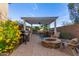 Outdoor kitchen with BBQ, bar seating, gas grill, and fire pit under pergola at 9231 W Bent Tree Dr, Peoria, AZ 85383
