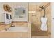 Bright bathroom featuring a bathtub and a glass-enclosed shower with tan ceramic tile surround at 9231 W Bent Tree Dr, Peoria, AZ 85383
