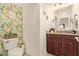 Charming powder room with floral wallpaper, granite countertop, decorative mirror, and toilet at 9231 W Bent Tree Dr, Peoria, AZ 85383
