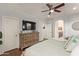 Large primary bedroom featuring hardwood floors, a ceiling fan, a dresser, and an ensuite bathroom at 9231 W Bent Tree Dr, Peoria, AZ 85383