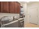 Laundry room featuring cabinets, shelves with baskets, and modern washer and dryer appliances at 9231 W Bent Tree Dr, Peoria, AZ 85383
