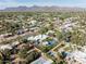 Aerial view of modern home, pool, and tennis court in desert neighborhood with mountain views in the distance at 9733 E Clinton St, Scottsdale, AZ 85260
