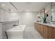 Bright bathroom featuring a soaking tub, walk-in shower, double vanities, and neutral tiling at 9733 E Clinton St, Scottsdale, AZ 85260