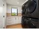 Well-lit laundry room featuring modern, high-efficiency, black stacked washer and dryer at 9733 E Clinton St, Scottsdale, AZ 85260
