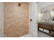 A modern shower stall with decorative herringbone tile and a view into the bathroom at 9733 E Clinton St, Scottsdale, AZ 85260