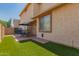 Backyard featuring a patio set, artificial grass, and a beige stucco exterior at 10055 E Isabella Ave, Mesa, AZ 85209