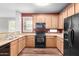 Functional kitchen with light wood cabinets, granite countertops, and black appliances at 10055 E Isabella Ave, Mesa, AZ 85209