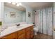 Inviting bathroom with single sink vanity, a large mirror, and a shower-tub combo with printed shower curtain at 1146 W Sea Fog Dr, Gilbert, AZ 85233