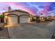 A beautiful property featuring a two-car garage and lush landscaping under a dramatic, colorful sunset sky at 1146 W Sea Fog Dr, Gilbert, AZ 85233