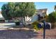 Charming home featuring a lush front yard with a mature olive tree and colorful landscaping at 12934 W Chapala Dr, Sun City West, AZ 85375