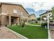Well-maintained backyard featuring synthetic grass, pavers, small palm tree, and covered outdoor seating area at 14318 N 142Nd Ln, Surprise, AZ 85379