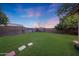 Expansive backyard featuring lush green lawn, privacy walls, and stepping stones at 15245 W Crocus Dr, Surprise, AZ 85379