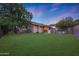 Large backyard with lush green lawn, mature trees, and view of the covered patio at 15245 W Crocus Dr, Surprise, AZ 85379