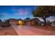 Charming home featuring three-car garage and inviting curb appeal with a mature shade tree at dusk at 15245 W Crocus Dr, Surprise, AZ 85379