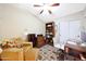 Bright office with ceiling fan, wood desk, shelving and chair, plus comfortable armchair and floral patterned rug at 15245 W Crocus Dr, Surprise, AZ 85379