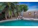 Close up of a tranquil backyard pool with stone waterfall feature and lush tropical plants at 15245 W Crocus Dr, Surprise, AZ 85379