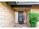 View of front door with black security door and green bushes, front door light, brick wall at 15424 N 52Nd Pl, Scottsdale, AZ 85254