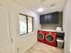 Bright laundry room with wood-look flooring, red washer/dryer set, dark cabinets, and natural light at 15602 N 37Th St, Phoenix, AZ 85032