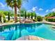 Beautiful pool with a rock slide feature surrounded by green landscaping and palm trees at 15602 N 37Th St, Phoenix, AZ 85032